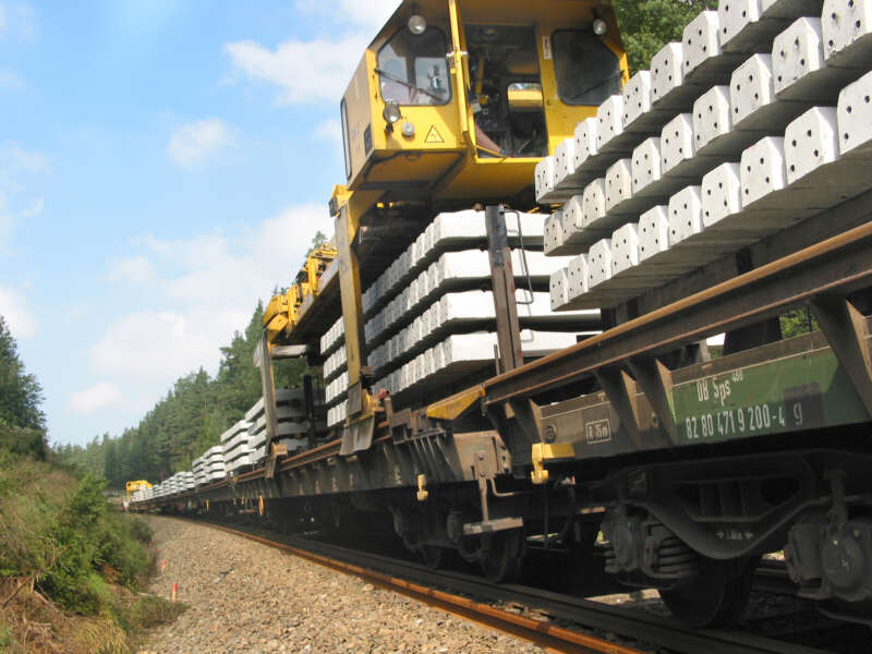 Gantry cranes transport new and old sleepers within the track under construction.